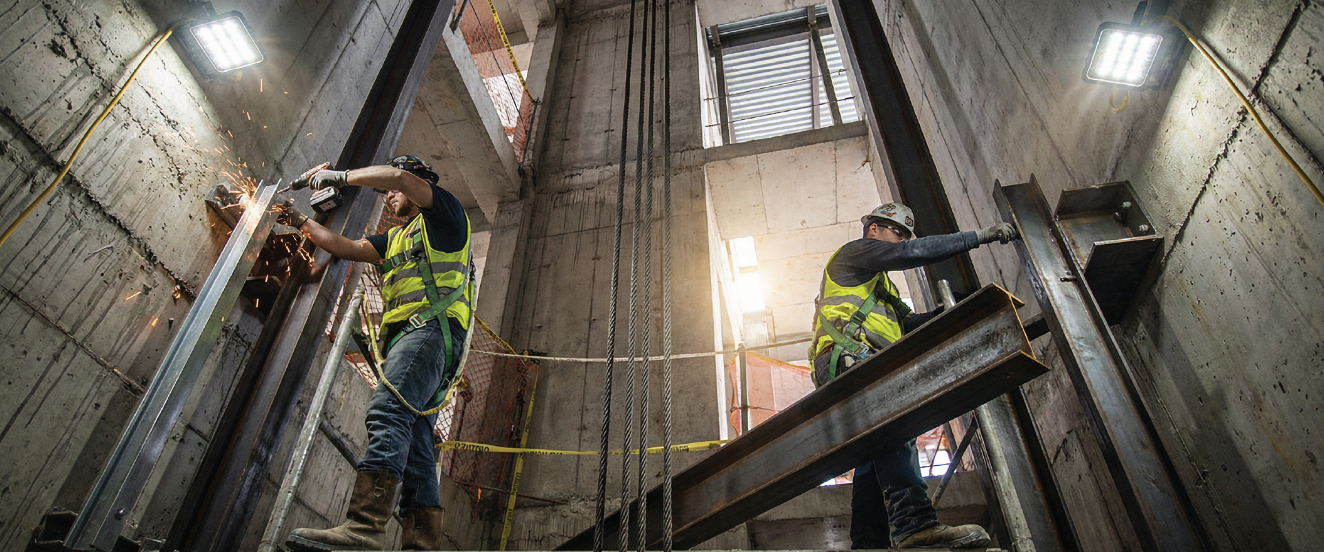 Elevator installation work in progress with technicians assembling lift shaft structure